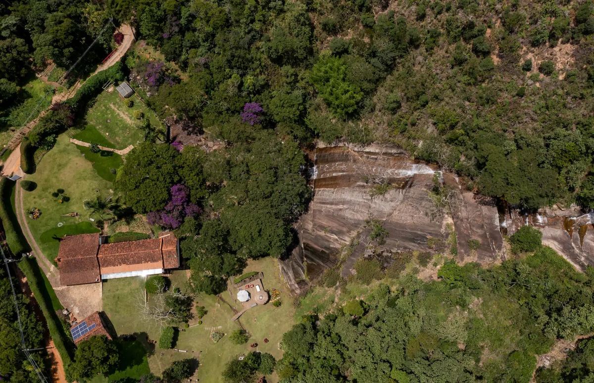 Vista aérea da propriedade, com a casa entre a mata e a cachoeira