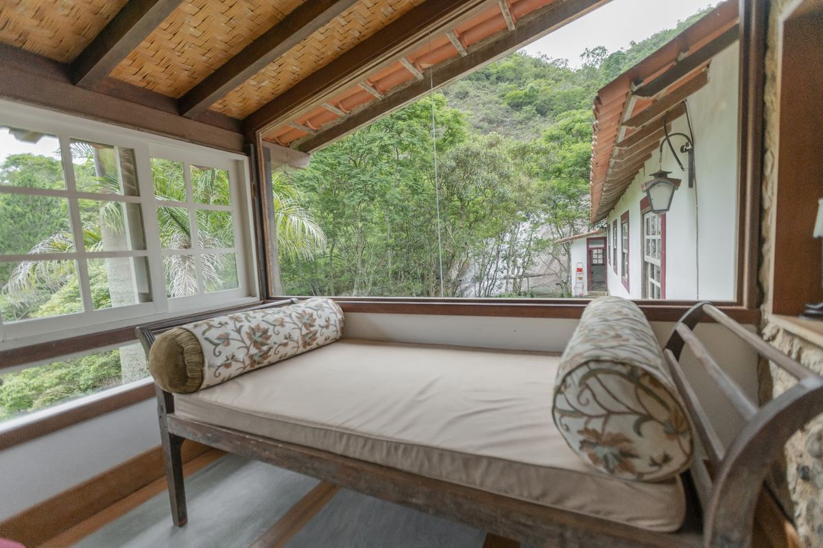Sala com sofá-cama e janelas para a mata